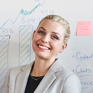 a woman smiling in front of a whiteboard